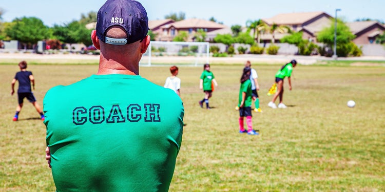 Youth soccer players and a volunteer coach on the field