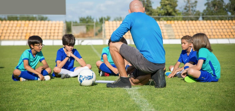 Youth soccer coach celebrating with players after a game