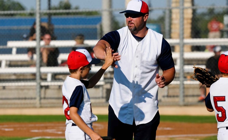 Youth baseball coach congratulating players
