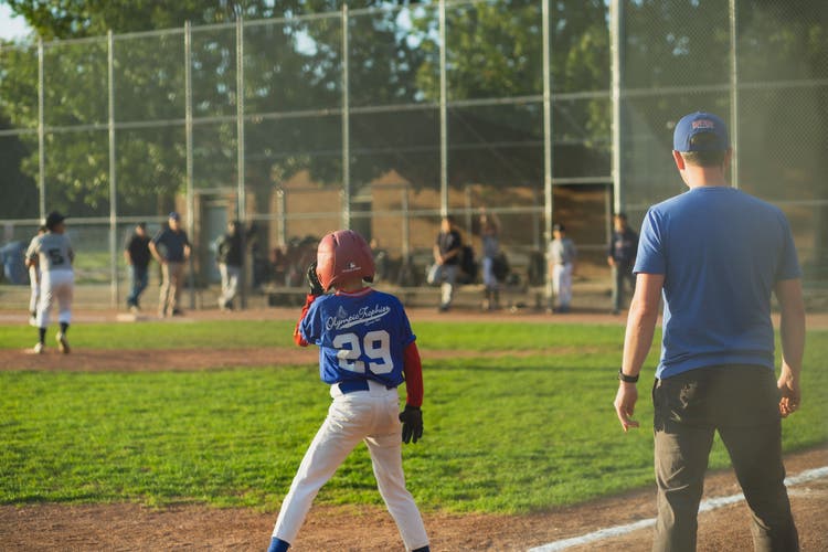 Youth baseball coach with players on the field during a game.