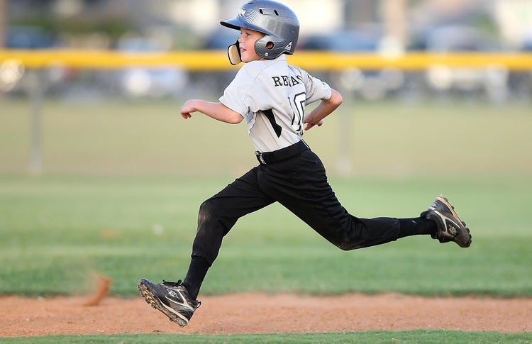 Youth baseball player running bases on the field.
