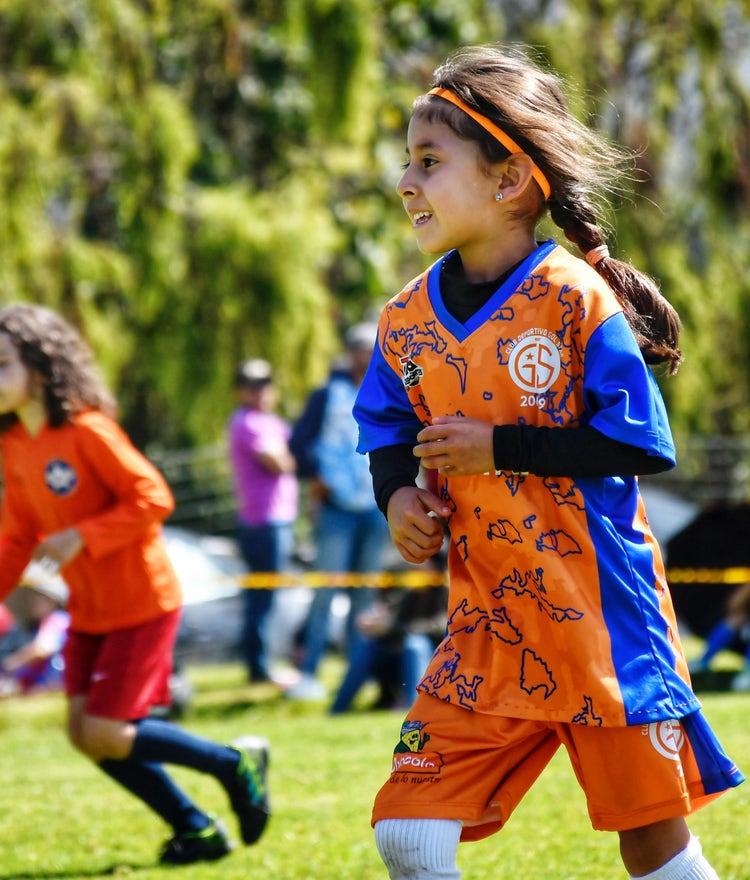 Young girl running in her soccer game, smiling